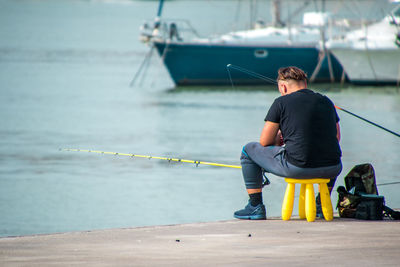 Rear view of man sitting on boat against sea