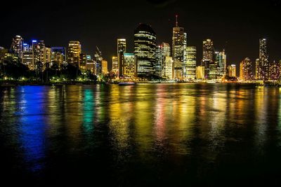 Illuminated buildings reflecting on river at night