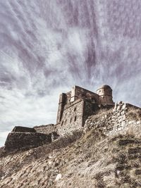 Low angle view of old ruin against cloudy sky