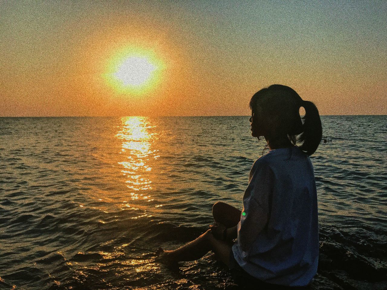 sunset, sea, horizon over water, water, rear view, scenics, sun, nature, tranquil scene, one person, beauty in nature, beach, sky, real people, tranquility, idyllic, silhouette, lifestyles, sitting, outdoors, clear sky, boys, standing, relaxation, vacations, men, people