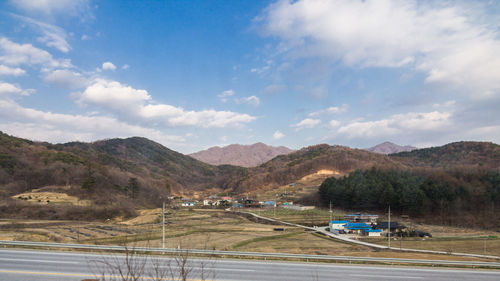 Cars on road by mountains against sky