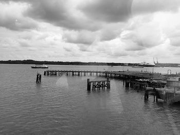 Pier in sea against cloudy sky