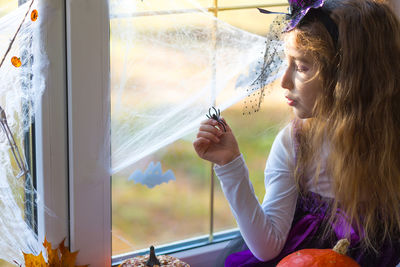 Side view of young woman looking through window