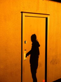 Close-up of silhouette person standing against yellow wall