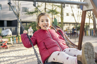 Portrait of girl sitting on swing at park