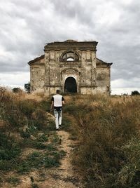 Man walking to ruined german church in ukrainian village. 