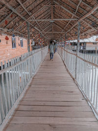 Rear view of man walking on footbridge