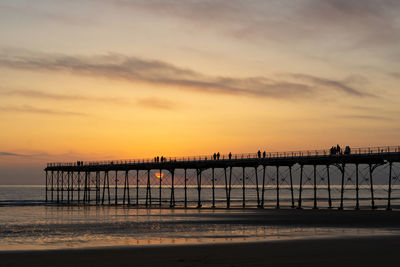 Pier over sea against sky during sunset