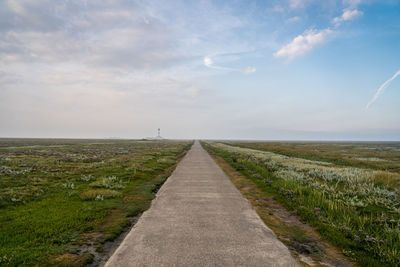 Road amidst field against sky