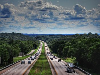 Cars on road amidst trees against sky