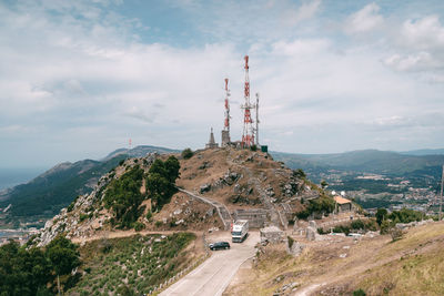 Windmill on road by mountain against sky