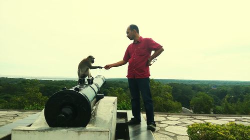 Full length of young woman standing on tree against sky