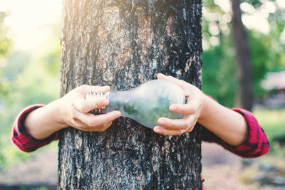 Midsection of woman holding tree trunk