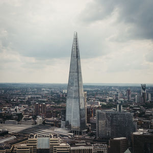 Aerial view of buildings in city against cloudy sky