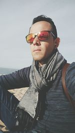 Young man wearing sunglasses while sitting at beach