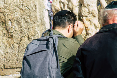 Rear view of friends standing against wall