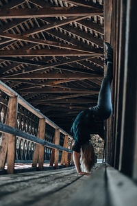 Rear view of woman sitting on railing