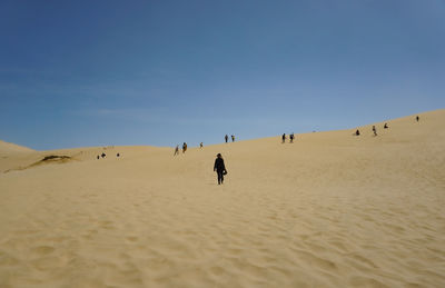 People at beach against clear sky