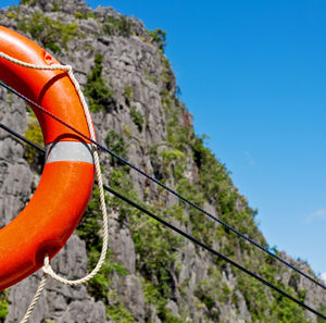 Low angle view of orange hanging on rope against sky