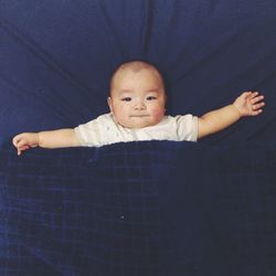 Portrait of baby relaxing on blue bed