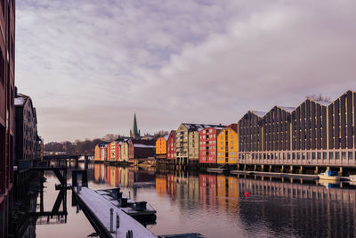 Bridge over river by buildings against sky in city