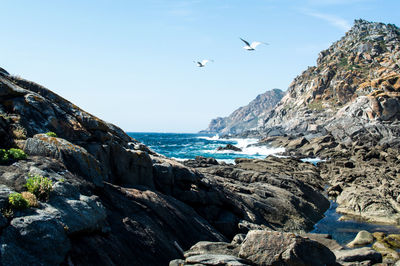 Rock formations by sea against sky