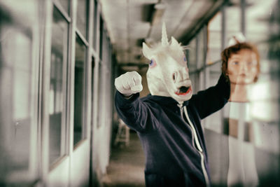 Man wearing horse mask standing in corridor