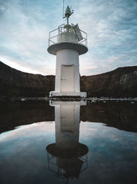 Lighthouse by lake against sky