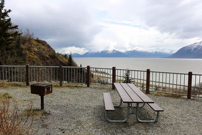Chairs and table by sea against sky