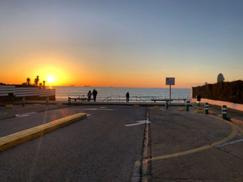 People on beach against sky during sunset