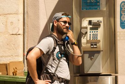 Man talking on payphone while standing outdoors