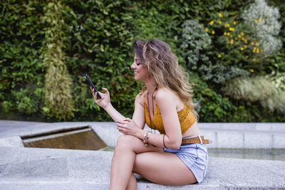 Full length of woman sitting on mobile phone