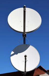 Low angle view of electricity pylon against clear blue sky