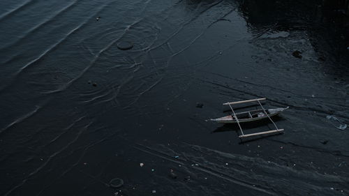 High angle view of abandoned boat floating on a polluted river.