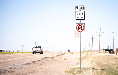 Road sign on street against clear sky