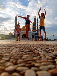 Low angle view of kids jumping against mosque