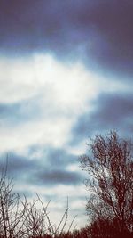 Low angle view of bare tree against cloudy sky