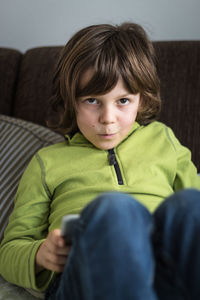 Portrait of boy using digital tablet while sitting on bed at home