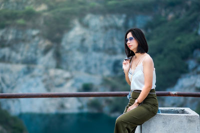 Young woman looking away while standing against railing