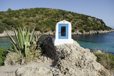 Built structure on rock by sea against sky