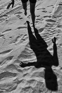 Low section of people walking on sand at beach