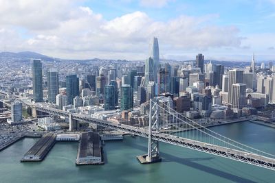 Aerial view of bridge over river and buildings against sky