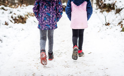 Low section of women walking on snow