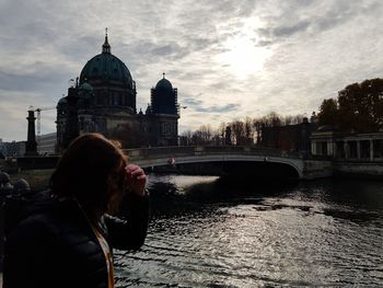 Rear view of man outside building against sky in city