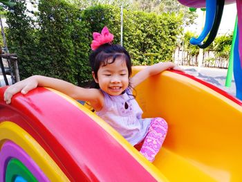 Cute smiling girl sitting on slide at playground