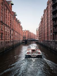 Canal amidst buildings in city against sky