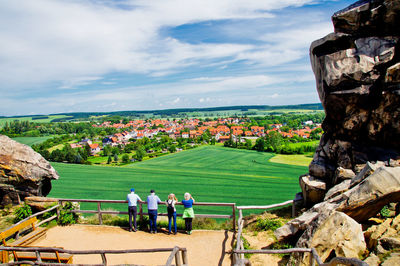 Four persons looking from teufelsmauer, harz mountains, in a scenic landscape with villages