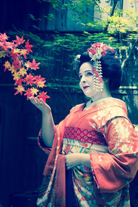 Woman wearing kimono standing by leaves