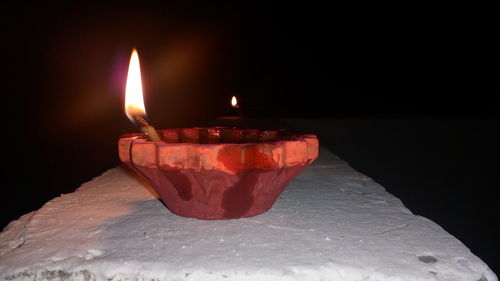 Close-up of illuminated candle against black background