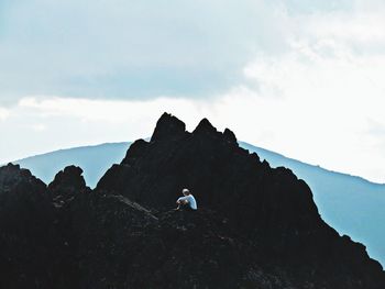 Low angle view of man standing on mountain against sky